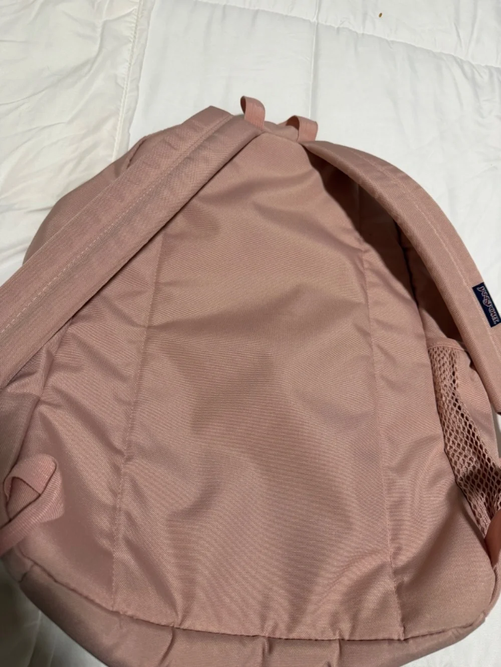 JanSport Cross Town backpack in a light pink color with a blue logo patch